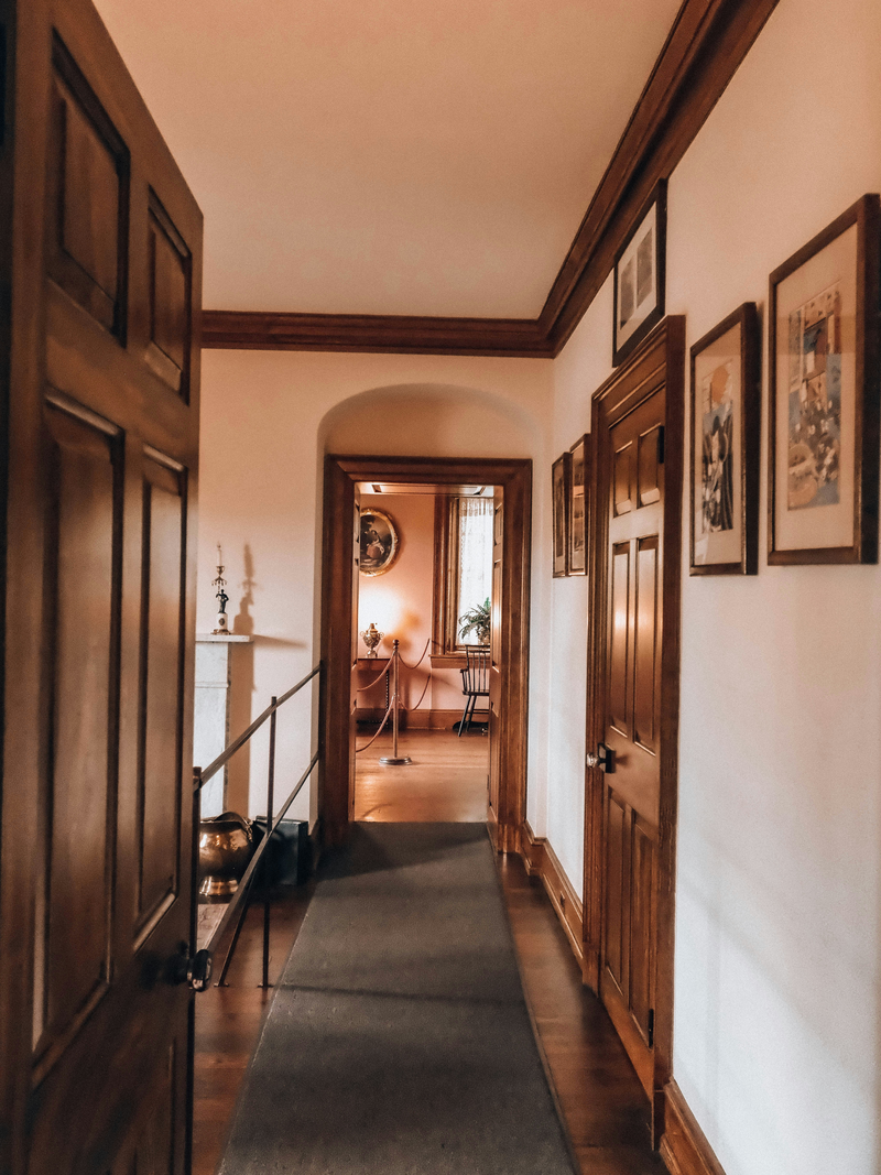 A period hallway with dark wood doors and framed art