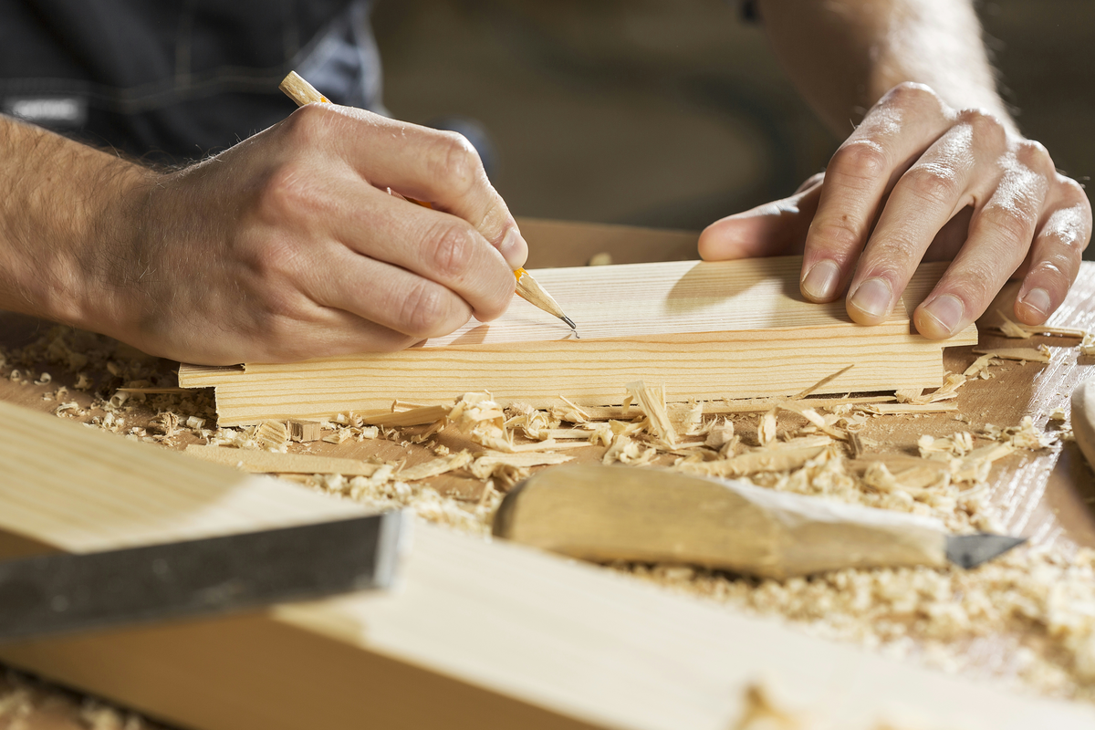 A craftsman marking a line on a wooden board